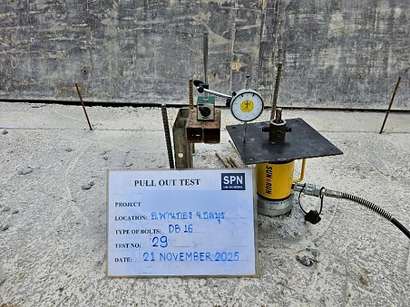 Pull-Out test setup at point 29 on a smooth concrete surface: a yellow hollow-plunger hydraulic jack on a steel bearing plate, a DB16 bar passing through the jack, a dial gauge on a magnetic stand mounted on a steel box section separate from the jack base, and a PULL OUT TEST sign dated 21 November 2025