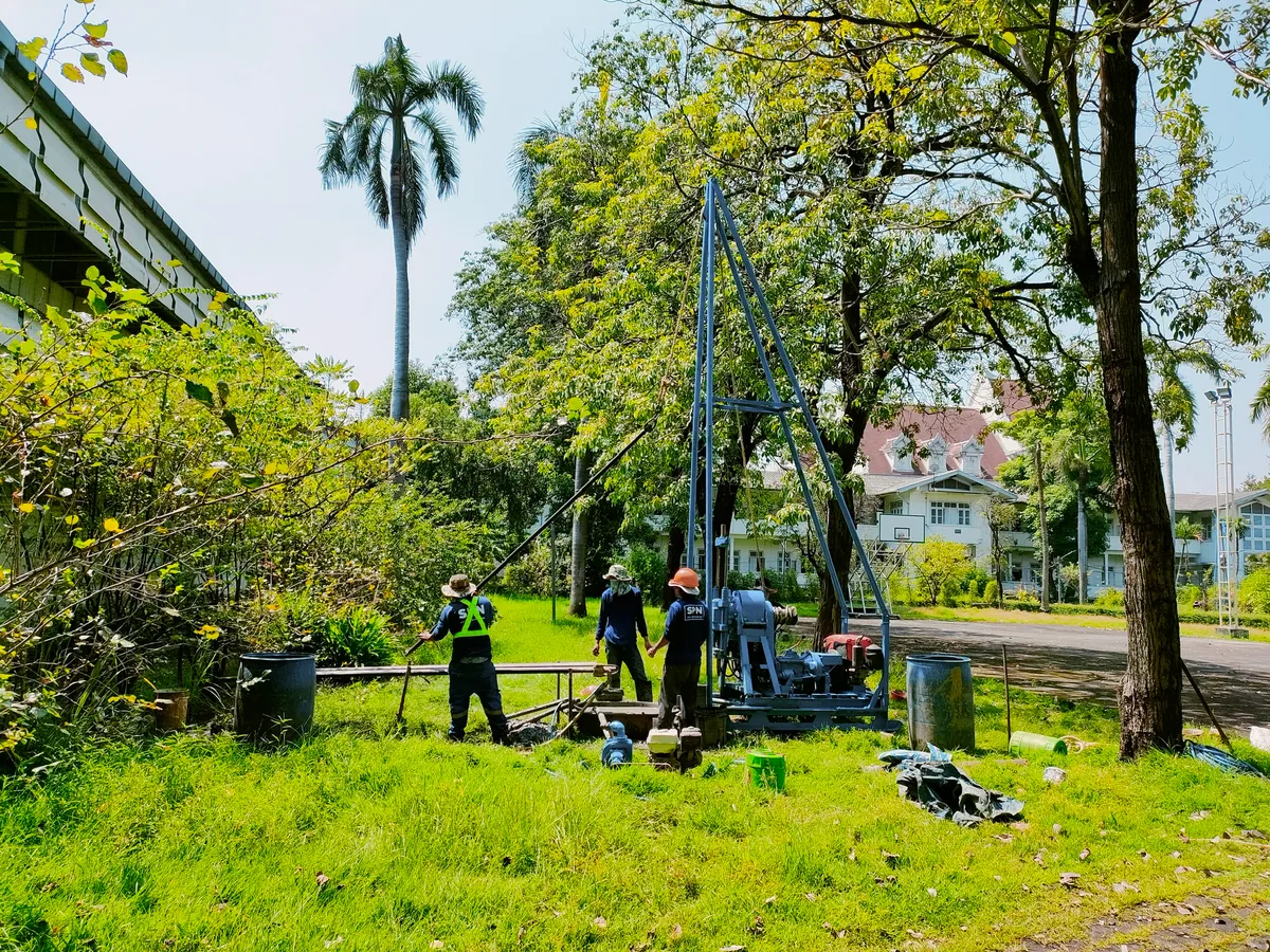 ทีมเจาะสำรวจดิน SPN ตั้งเครื่องเจาะแบบสามขาบนพื้นที่สวนที่เคลียร์เรียบร้อยแล้ว พร้อมถังน้ำและอุปกรณ์ครบชุด