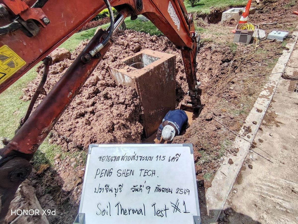 หลุมทดสอบ Soil Thermal Test จุดที่ 1 ขุดด้วยรถขุดขนาดเล็กลงถึงระดับ 3 เมตร ข้างฐานเสาไฟฟ้า มีป้ายระบุโครงการขยายเขตสายส่ง 115 kV จังหวัดปราจีนบุรี