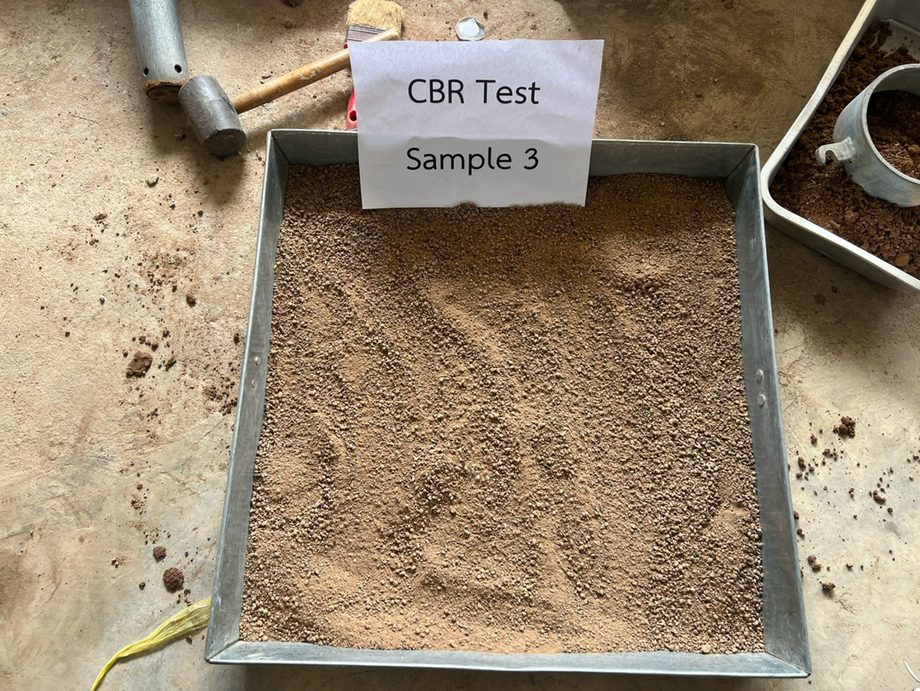 ตัวอย่างดินร่อนผ่านตะแกรงเตรียมในถาดพร้อมค้อนบดอัด สำหรับทดสอบ CBR ตามมาตรฐาน ASTM D1883 ในห้องปฏิบัติการของ SPN