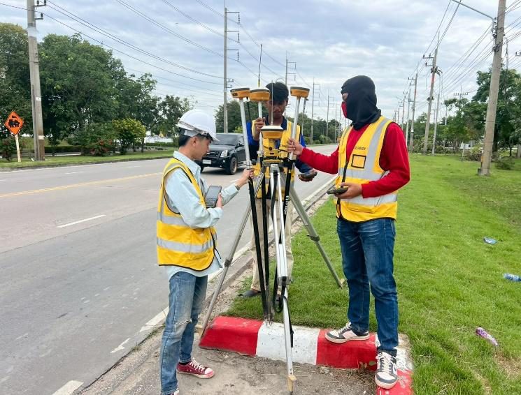วิศวกรสำรวจ SPN สวมเสื้อสะท้อนแสงรังวัดด้วยเครื่องเดินสำรวจ GPS RTK (GNSS Rover) ในพื้นที่โครงการ